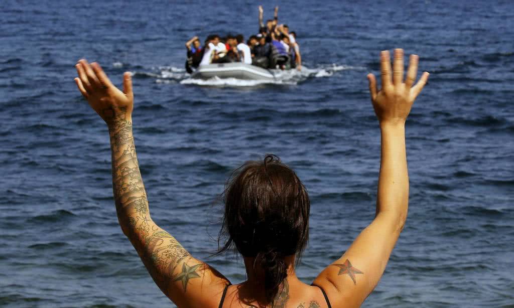 Μια εθελόντρια κάνει σήμα στη φουσκωτή βάρκα με τους Αφγανούς μετανάστες στη Λέσβο. Γιάννης Μπεχράκης