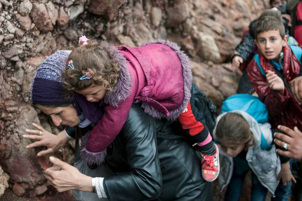 Μία πρόσφυγας κουβαλά το παιδί της, σε μια βραχώδη παραλία της Λέσβου, έχοντας μόλις φτάσει από την Τουρκία - 11/10/2015 /Φώτης Πλέγκας/ Reuters